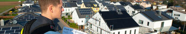 e-netz-Mitarbeiter hält einen Bebauungsplan in der Hand und blickt auf Neubauten der Solarsiedlung in Groß-Umstadt
