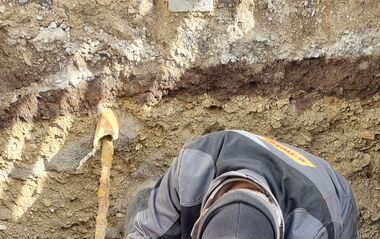 e-netz-Mitarbeiter arbeitet an einem Rohr in einer Grube.