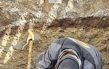 e-netz-Mitarbeiter arbeitet an einem Rohr in einer Grube.