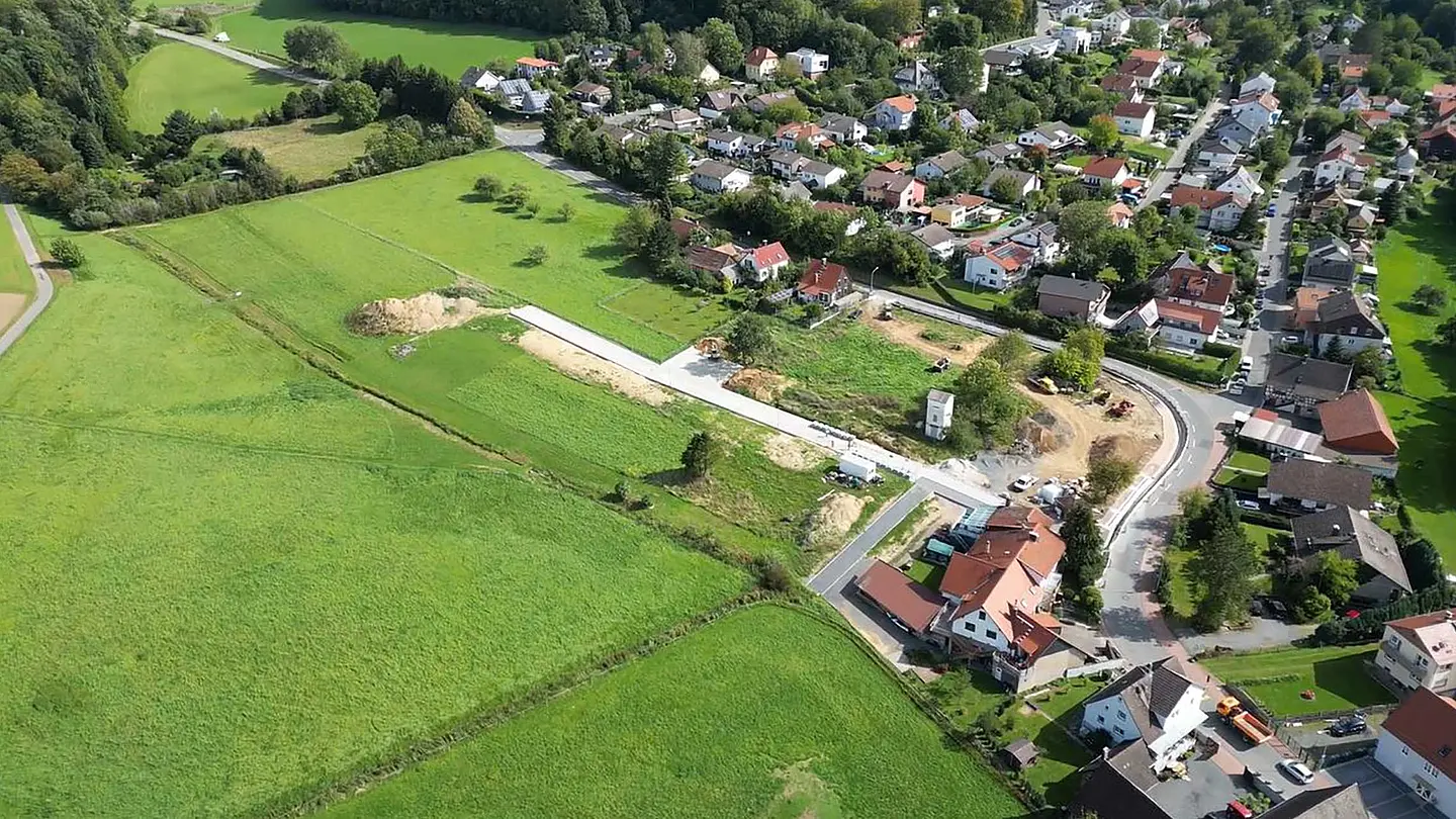 Luftaufnahme zeigt eine Siedlung mit Gärten und angrenzenden Feldern.