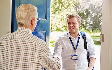 Kunde öffnet einem Ableser die Tür für die Vor-Ort-Ablesung des Zählerstandes