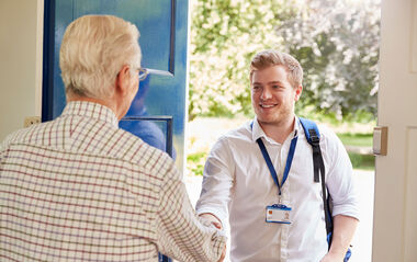 Kunde öffnet einem Ableser die Tür für die Vor-Ort-Ablesung des Zählerstandes