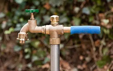 Standrohr aus Messing mit blauem Griff an einem Metallrohr für Bauwasser.