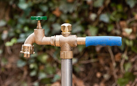 Standrohr aus Messing mit blauem Griff an einem Metallrohr für Bauwasser.