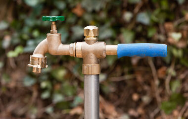 Standrohr aus Messing mit blauem Griff an einem Metallrohr für Bauwasser.