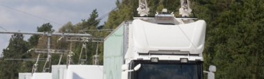 LKWs werden auf einer Autobahn über Oberleitungstechnik direkt mit Energie versorgt.