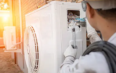 Ein Techniker wartet eine Wärmepumpe im Freien.