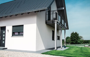 Nahaufnahme eines neugebauten Einfamilienhauses mit grauem Dach und Balkon