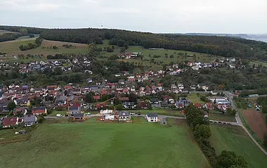 Luftaufnahme zeigt eine ländliche Siedlung mit Fachwerkhäusern und Feldern.