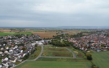 Luftaufnahme zeigt eine ländliche Szene mit Feldern, Wiesen und einem Dorf.