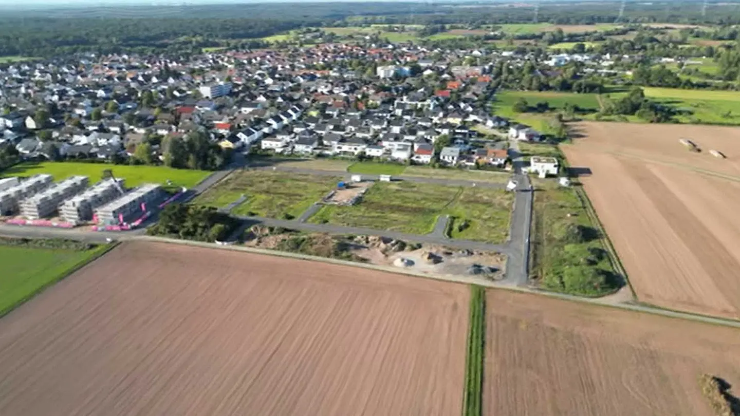 Baustelle mit Wohnbebauung und angrenzenden Feldern aus der Vogelperspektive.