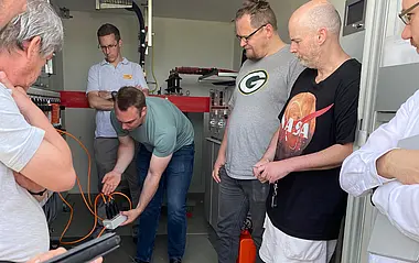 Fachleute der e-netz schauen sich Geräte in einem technischen Raum an.