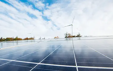 Nahaufnahme einer Solaranlage mit Blick auf eine Windenergieanlage