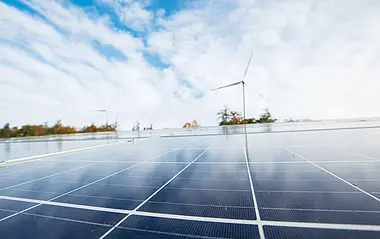 Nahaufnahme einer Solaranlage mit Blick auf eine Windenergieanlage