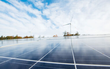 Nahaufnahme einer Solaranlage mit Blick auf eine Windenergieanlage