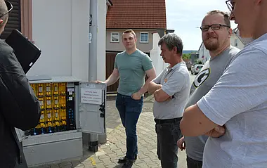 Techniker inspizieren eine elektrische Verteileranlage im Freien.