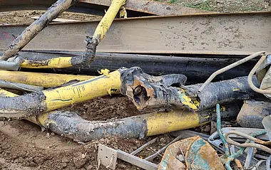 Beschädigte Rohre liegen auf einer Baustelle.