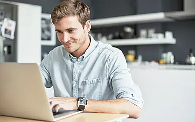 Mann sitzt vor seinem Laptop in seiner Wohnung