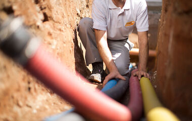 e-netz-Monteur verlegt Rohre für den Mehrspartenhausanschluss im Kabelgraben