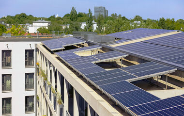 Solarmodule auf einem Flachdach integriert, mit Blick auf eine städtische Umgebung.