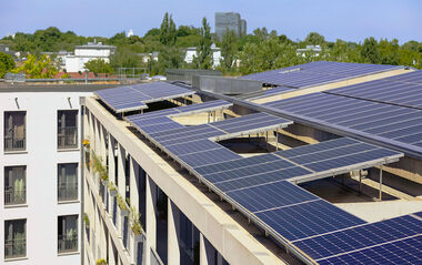 Solarmodule auf einem Flachdach integriert, mit Blick auf eine städtische Umgebung.