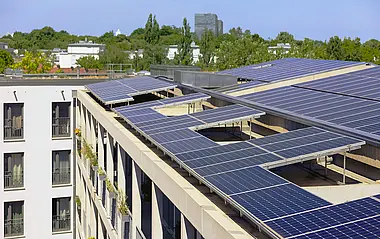 Solarmodule auf einem Flachdach integriert, mit Blick auf eine städtische Umgebung.
