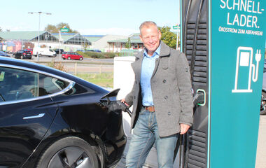 Ralf Möller, Bürgermeister der Stadt Weiterstadt, steht neben einer blauen E-Ladestation im Freien.