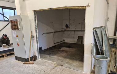 Technikraum mit Rohrleitungen und Elektroschrank, teilweise renoviert.