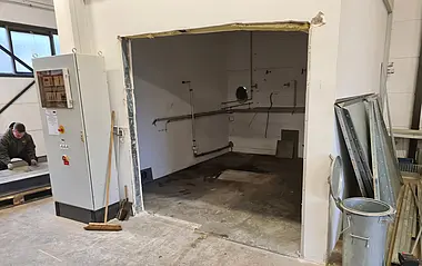 Technikraum mit Rohrleitungen und Elektroschrank, teilweise renoviert.