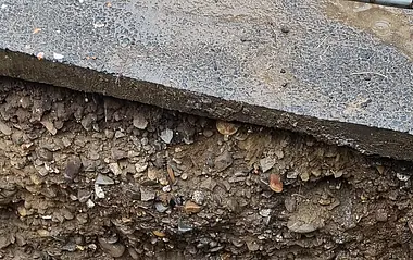 Baugrube mit verlegten Rohren und Wasseransammlung.