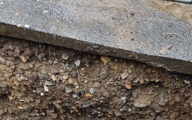 Baugrube mit verlegten Rohren und Wasseransammlung.