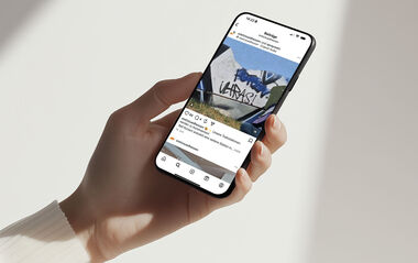 Eine Hand hält ein Smartphone, auf dessen Bildschirm ein Social-Media-Beitrag angezeigt wird.