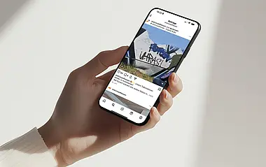 Eine Hand hält ein Smartphone, auf dessen Bildschirm ein Social-Media-Beitrag angezeigt wird.