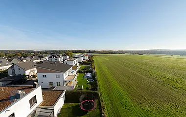 Wohngebiet grenzt an weiten, grünen Wiesen und Feldern.