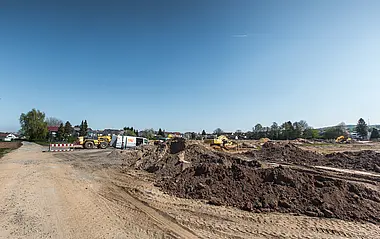 Bauarbeiten mit schwerem Gerät auf einer vorbereiteten Baustelle.