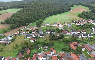 Luftaufnahme zeigt eine Wohngegend mit Häusern, Straßen und Grünflächen.