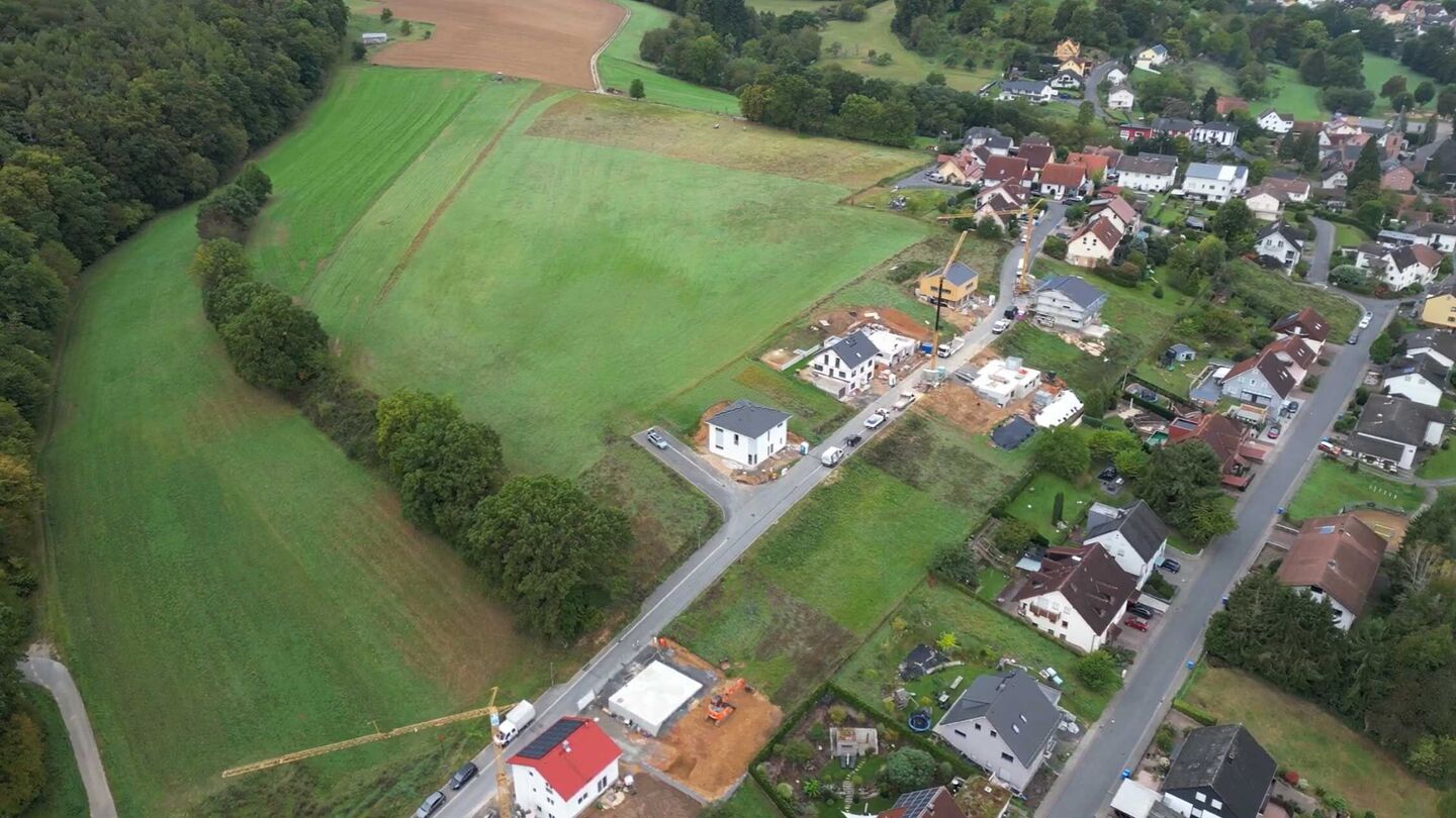 Drohnenaufnahme zeigt eine Wohnsiedlung mit Neubauten und Baustellen im Grünen.