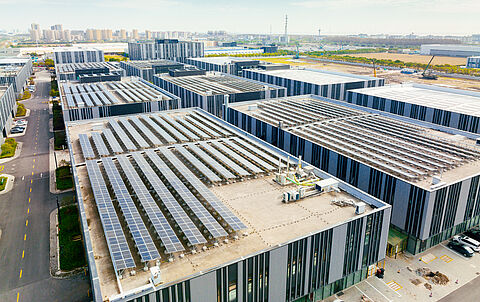 Satellitenansicht zeigt eine moderne Industrieanlage mit Solaranlagen auf dem Dach.