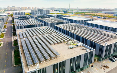 Satellitenansicht zeigt eine moderne Industrieanlage mit Solaranlagen auf dem Dach.