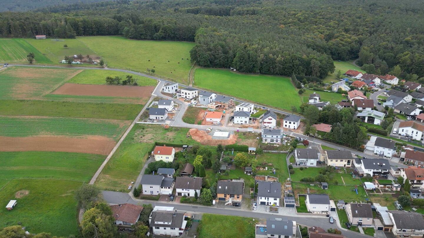 Luftaufnahme zeigt eine Wohnsiedlung mit Häusern und Grünflächen.