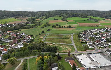 Luftaufnahme zeigt eine Wohnsiedlung mit Gewerbegebiet und angrenzenden Feldern.