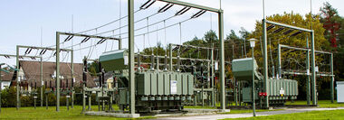 Umspannanlage mit Wohnhäusern und Bäumen im Hintergrund.