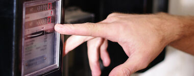 Finger zeigt auf den Zählerstand eines mechanischen Zählers