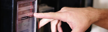 Finger zeigt auf den Zählerstand eines mechanischen Zählers