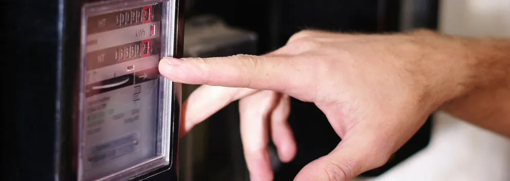 Finger zeigt auf den Zählerstand eines mechanischen Zählers